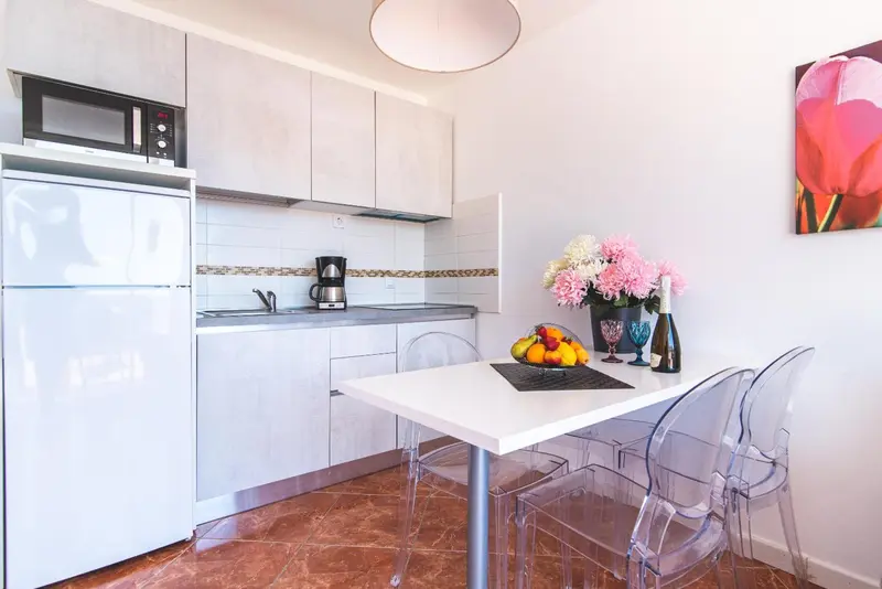 Une kitchenette lumineuse avec un réfrigérateur, un micro-ondes et une table à manger.