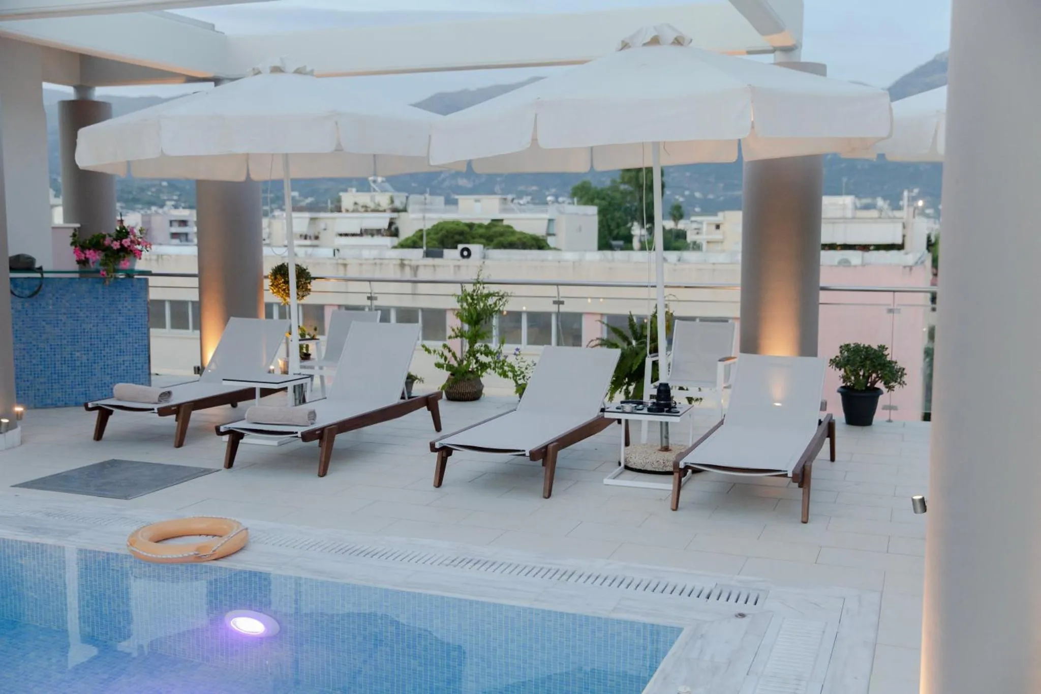 Transats blancs disposés autour d'une piscine sur une terrasse ensoleillée.