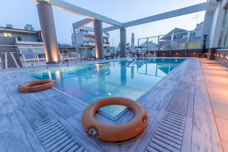 Une piscine rectangulaire bordée d'un sol carrelé et de chaises longues.