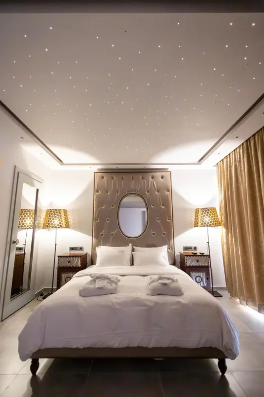 Une chambre lumineuse avec un grand lit et un décor mural étoilé.