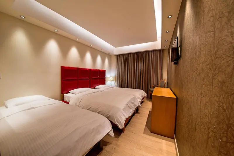 Une chambre lumineuse avec deux lits simples et une commode.