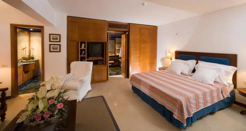 Une chambre lumineuse avec un grand lit et un fauteuil.