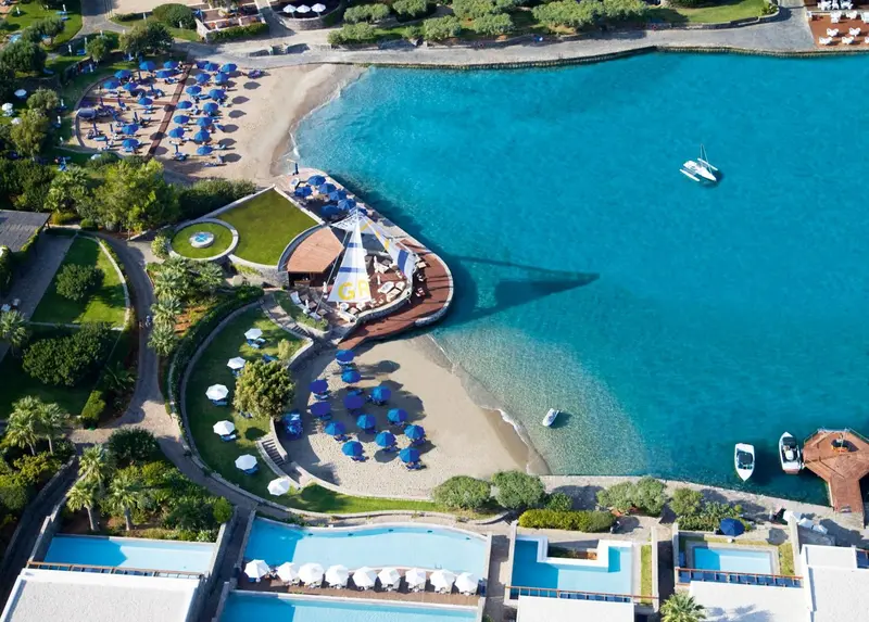 Vue aérienne d'une plage de sable fin bordée d'eaux turquoise et d'un complexe hôtelier.