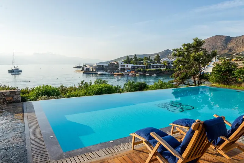 Une piscine à débordement offre une vue sur la mer et un port de plaisance.