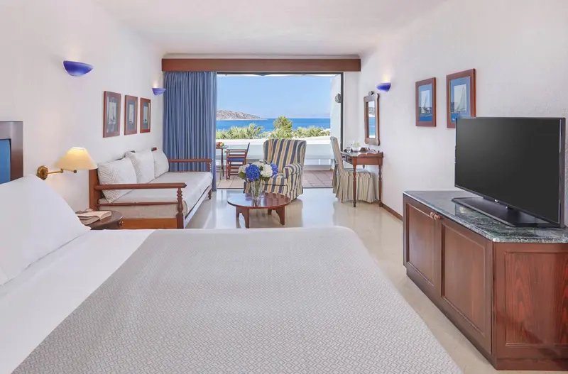 Une chambre lumineuse avec un coin salon et vue sur la mer.
