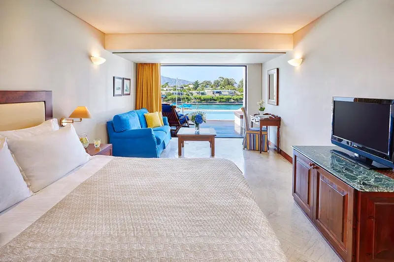 Chambre lumineuse avec un canapé bleu et une vue sur un paysage marin.