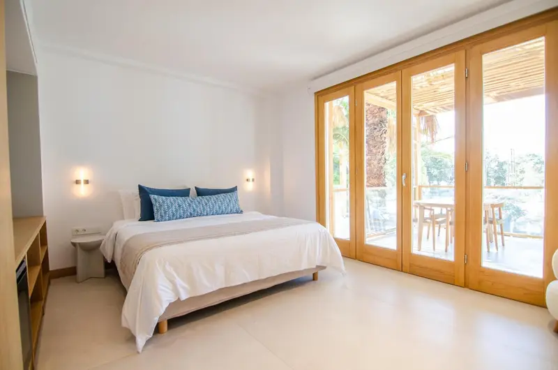 Une chambre lumineuse avec un grand lit et un accès à une terrasse.