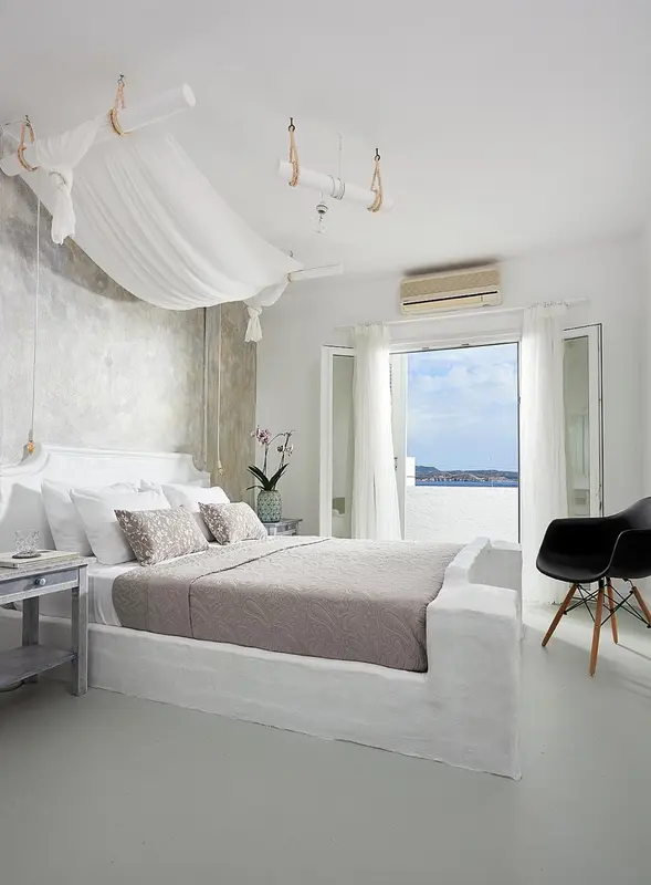 Une chambre lumineuse avec un grand lit à baldaquin et une vue sur la mer.