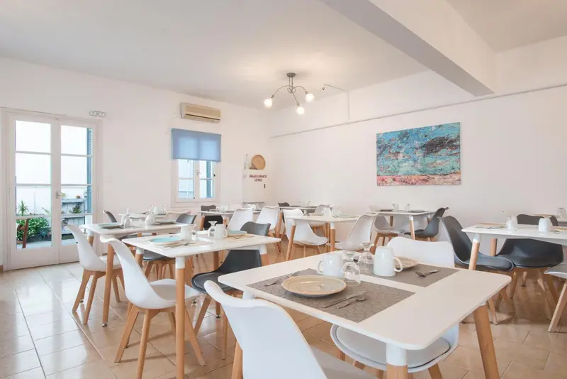 Une salle lumineuse avec des tables dressées pour le repas.
