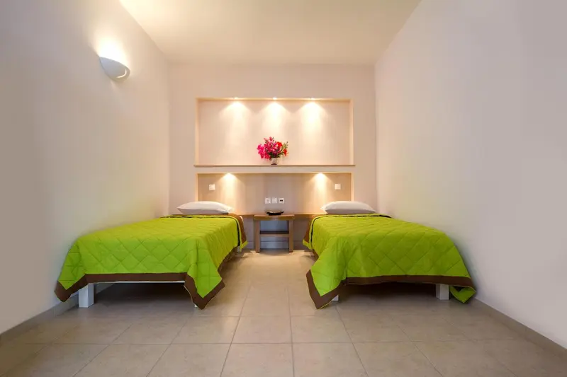 Deux lits simples verts dans une chambre lumineuse.