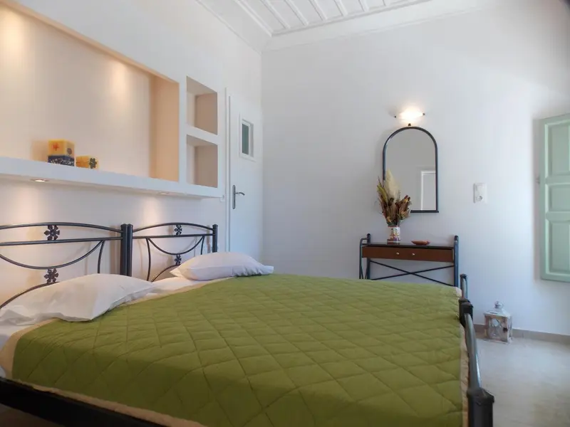 Une chambre lumineuse avec un lit recouvert d'une courtepointe verte et un miroir mural.