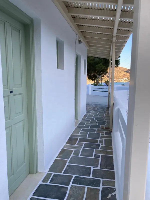 Allée couverte menant à des portes d'entrée dans un bâtiment blanc.