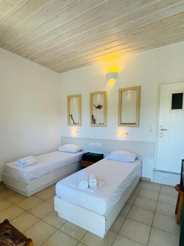 Une chambre lumineuse avec deux lits simples et des cadres décoratifs.