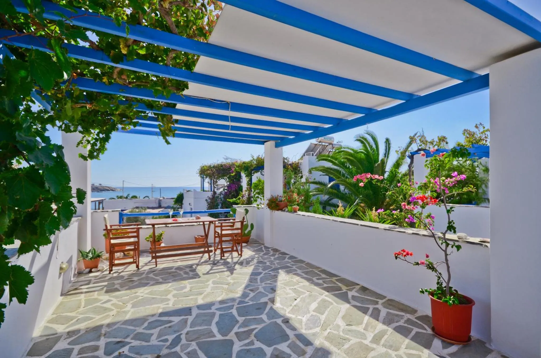 Terrasse ombragée avec table et chaises donnant sur la mer.