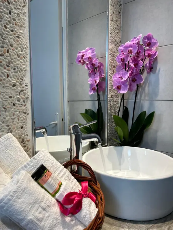Une salle de bain moderne avec des orchidées roses et des serviettes blanches.