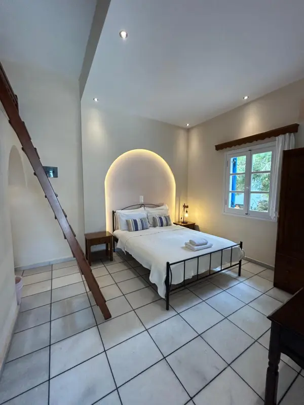 Une chambre lumineuse avec un lit blanc et une fenêtre bleue.