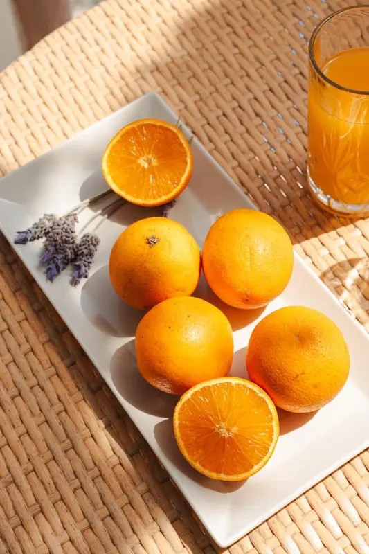 Assiette de tranches et d'oranges entières, accompagnées de lavande, sur une table en osier.