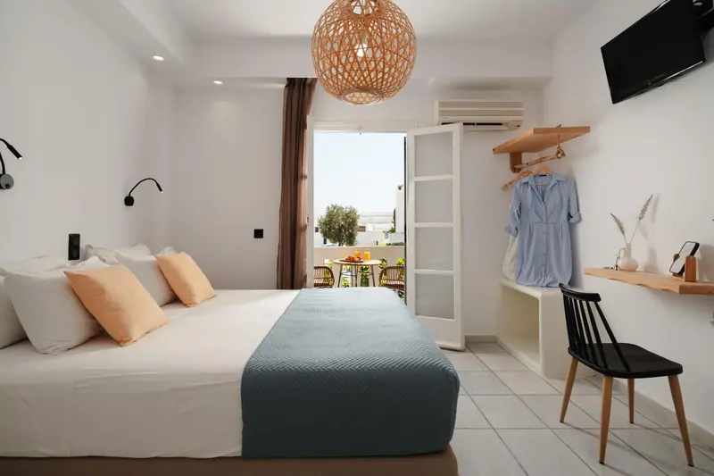 Une chambre lumineuse avec un lit fait et un accès à un balcon.