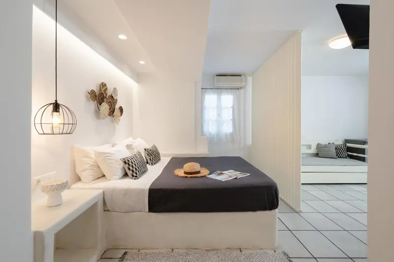 Une chambre lumineuse avec un grand lit et une décoration minimaliste.