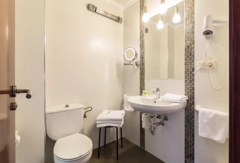 Une salle de bain claire avec des serviettes pliées et un miroir éclairé.