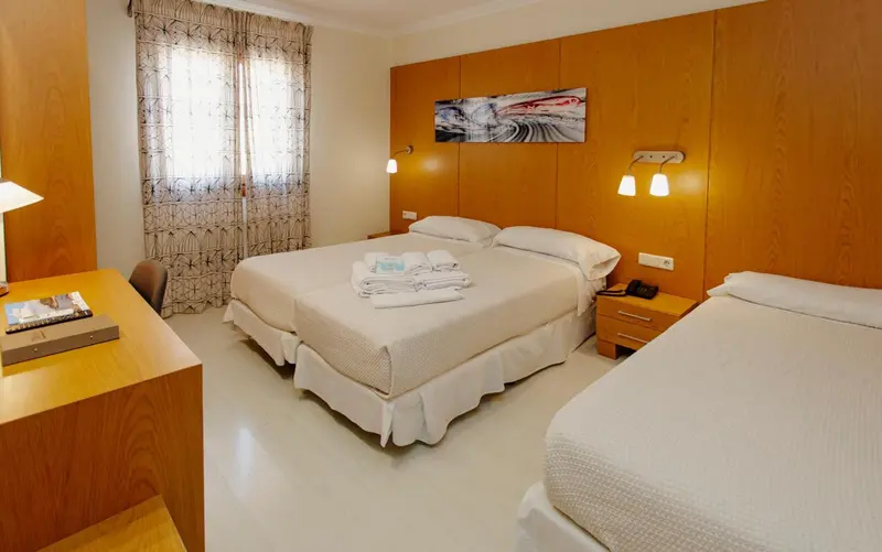 Une chambre lumineuse avec un grand lit et un bureau.