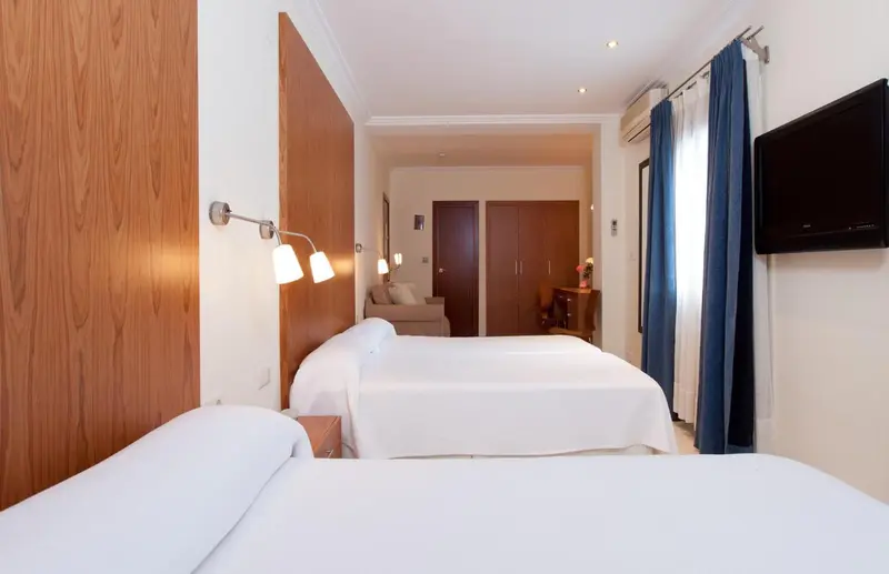 Une chambre lumineuse avec deux lits simples et un mur en bois.