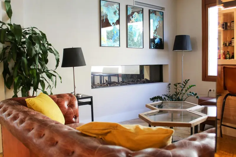 Un salon chaleureux avec un canapé en cuir, des tables basses et des œuvres d'art murales.