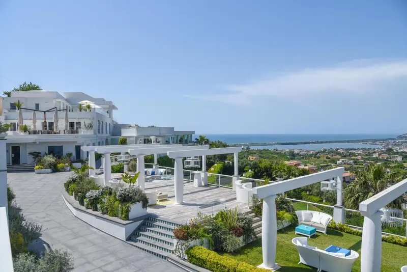 Terrasse blanche avec mobilier d'extérieur surplombant la mer et la côte.
