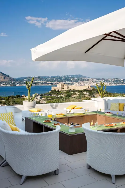 Une table est dressée sur une terrasse avec vue sur la mer et la côte.