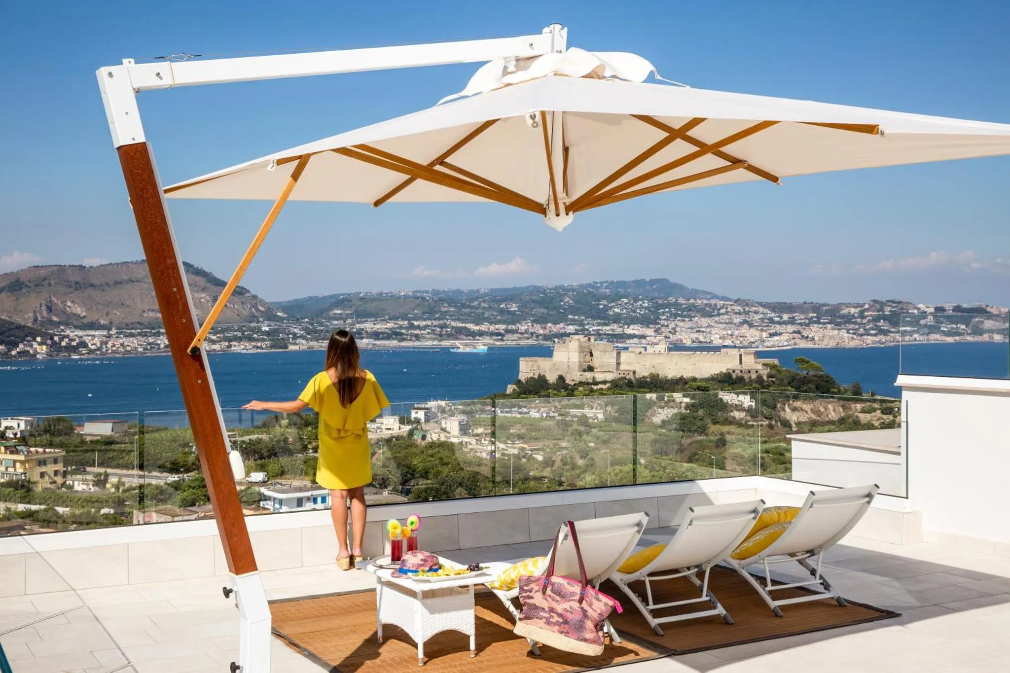 Terrasse avec transats et vue sur la mer et la ville.