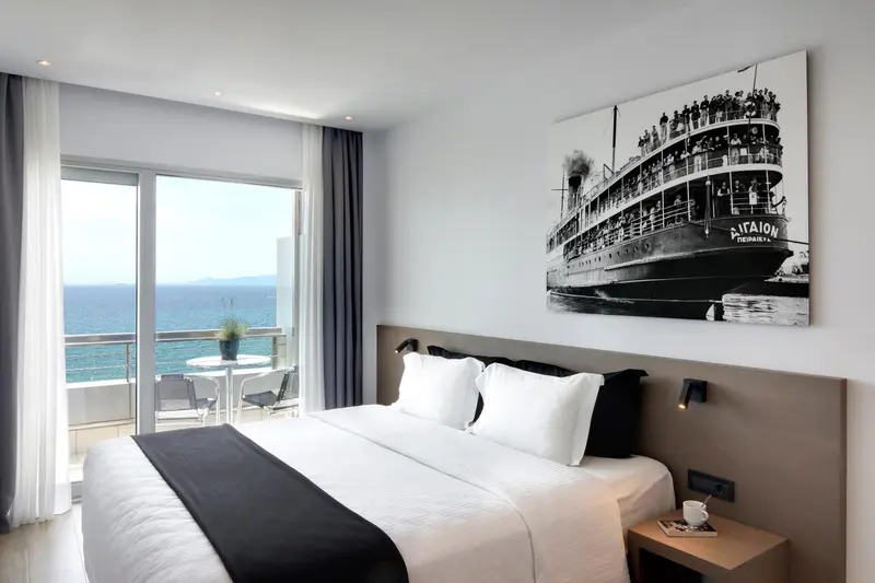 Chambre lumineuse avec un grand lit et vue sur la mer.