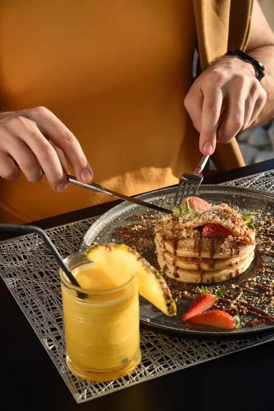 Assiette de pancakes aux fruits frais et verre de jus d'orange.