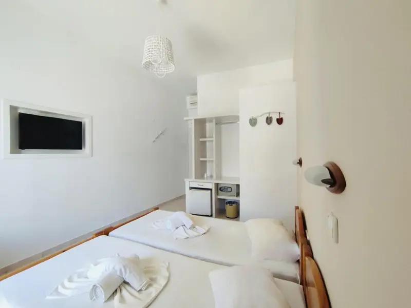 Une chambre lumineuse avec deux lits simples et un meuble de rangement.