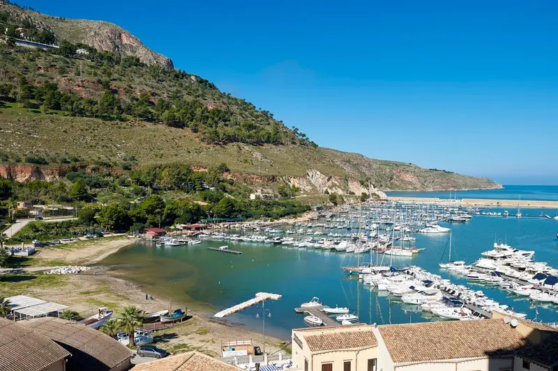 Vue d'un port de plaisance abrité au pied de collines verdoyantes.