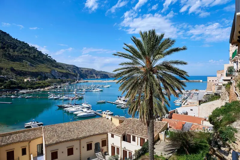 Vue sur un port de plaisance ensoleillé avec des bateaux amarrés et des bâtiments colorés.