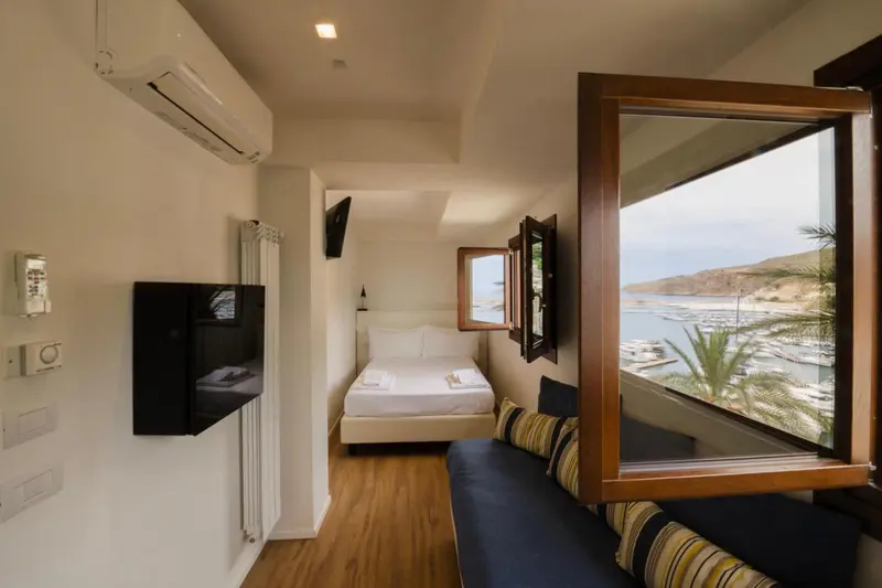 Une chambre lumineuse avec un lit et un canapé donnant sur une vue mer.