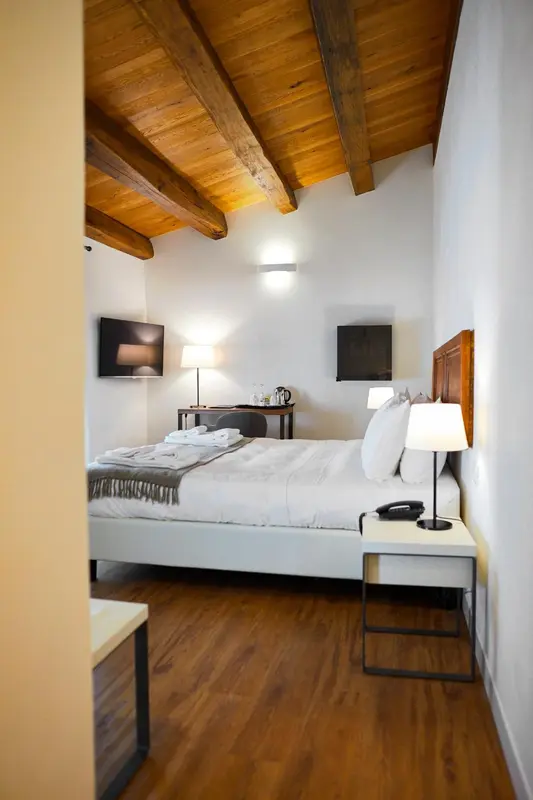 Une chambre lumineuse avec un lit double et une télévision murale.
