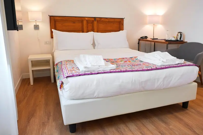 Une chambre lumineuse avec un grand lit recouvert d'une courtepointe colorée.