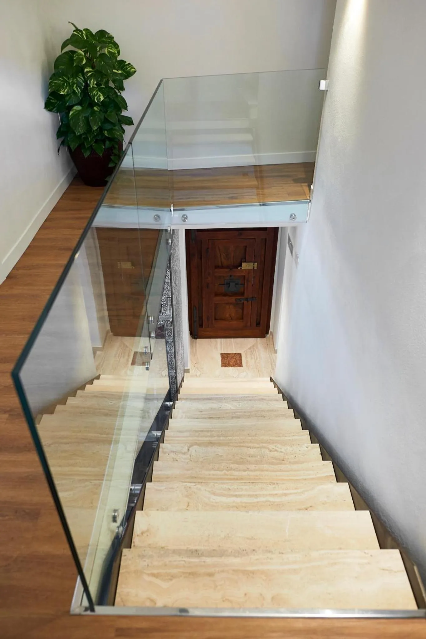 Escalier intérieur en pierre et bois avec garde-corps en verre.