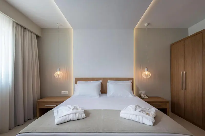 Une chambre lumineuse avec un grand lit et des luminaires suspendus.