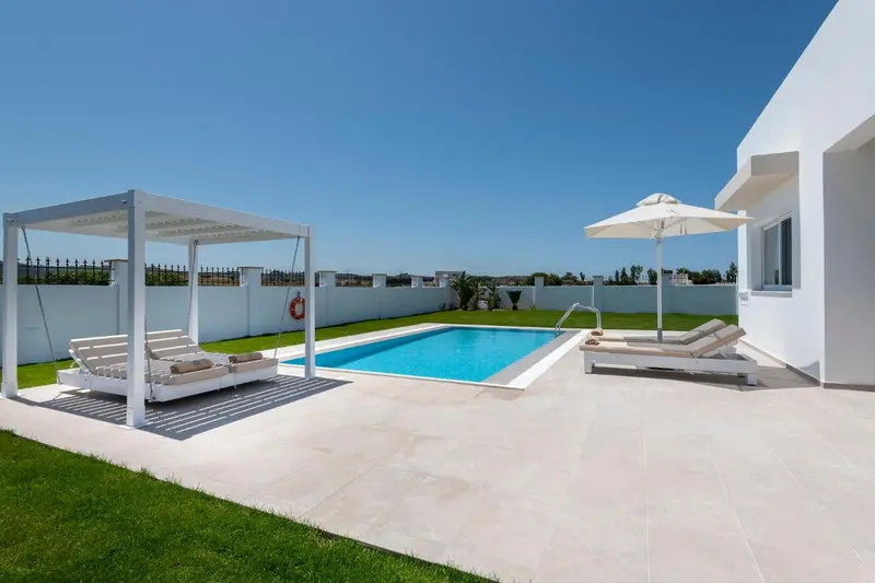 Terrasse avec transats et piscine ensoleillée.