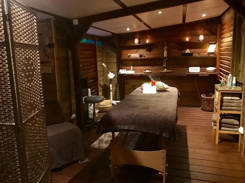 Espace de relaxation avec table de massage et décoration florale.