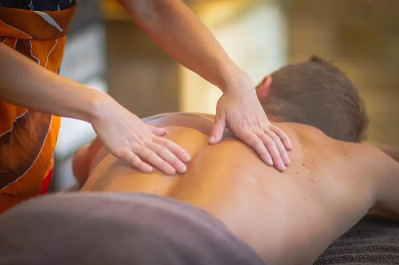 Un massage relaxant est pratiqué sur le dos d'une personne allongée.