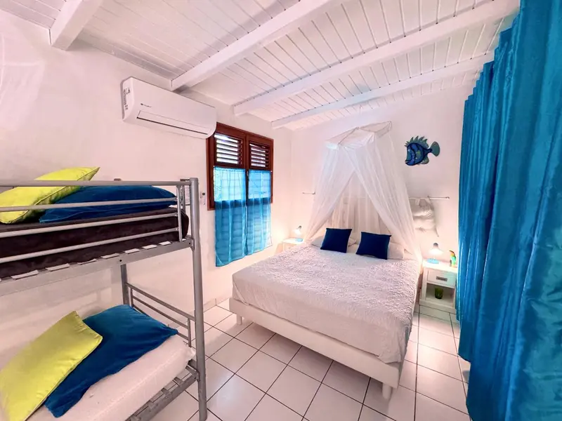 Une chambre lumineuse avec un lit superposé et un lit double à moustiquaire.