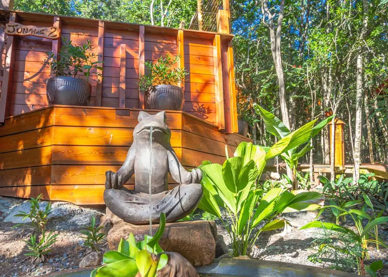 Une statue de grenouille en pierre est posée devant un bâtiment en bois.