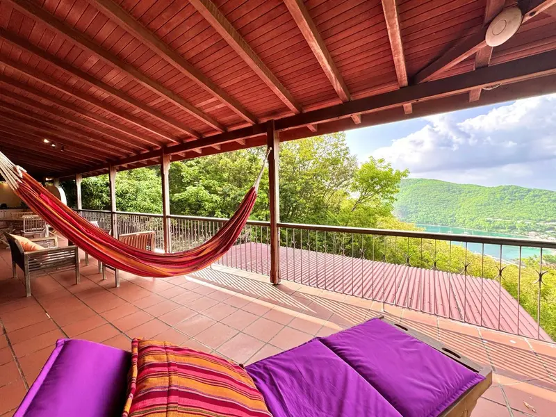 Terrasse ombragée avec hamac et vue sur la végétation et la mer.