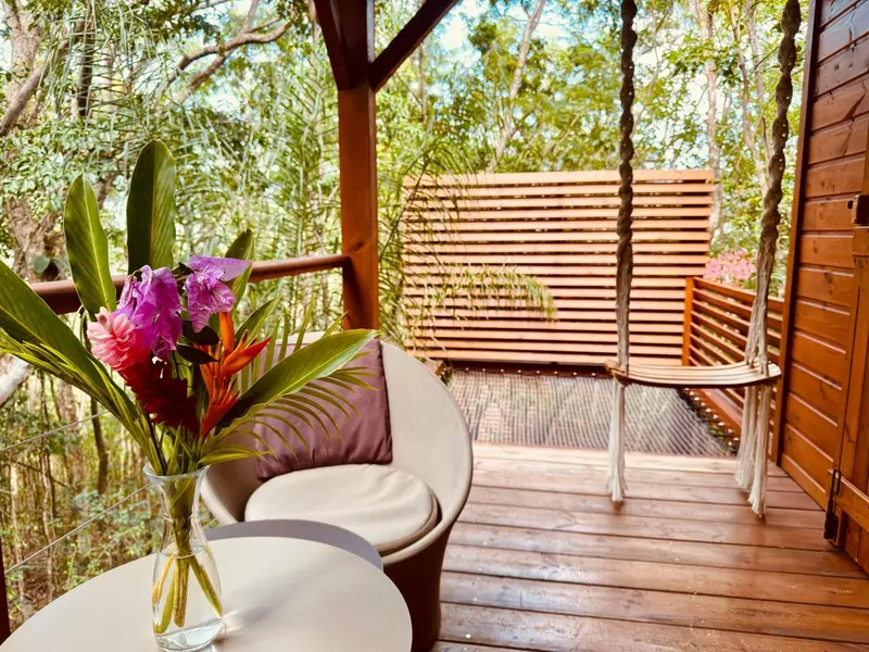 Une terrasse en bois avec des fauteuils et une balancelle.