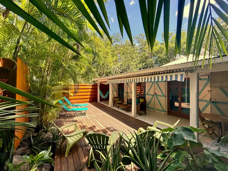 Terrasse en bois avec mobilier de jardin et bâtiment à l'arrière.