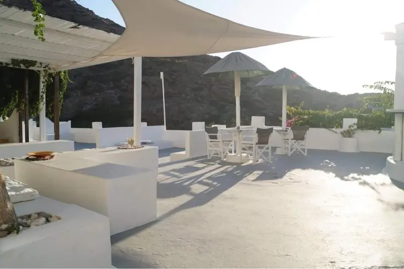 Terrasse ombragée avec mobilier blanc et vue sur un paysage montagneux.