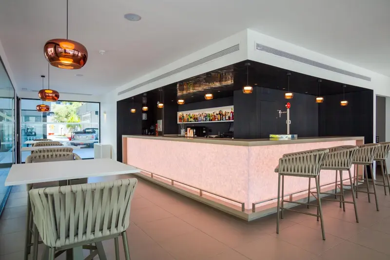 Un bar moderne avec un comptoir illuminé et des tabourets.